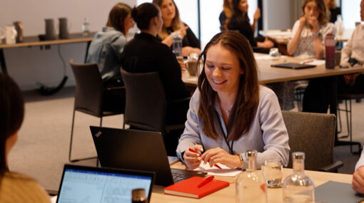 graduate smiling in a Hugh James training session surrounded by peers