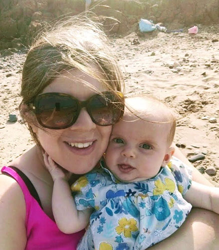 Anna Higham, a Partner in our clinical negligence department, sits on the beach on a sunny say with her daughter, Isabella, at a few weeks old, on her lap