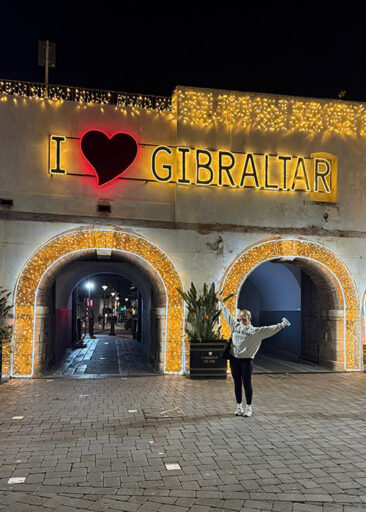 Hugh James trainee Catherine Adamec poses at night underneath an illuminated "I love Gibraltar" sign during her international secondment placement with BetVictor in Gibraltar