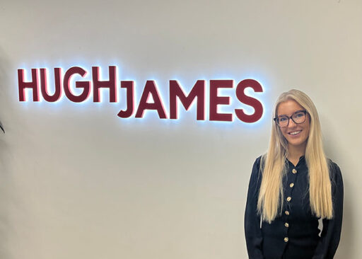 BetVictor's Ruby Duncalf stand next to an illuminated Hugh James logo in Hugh James' London office